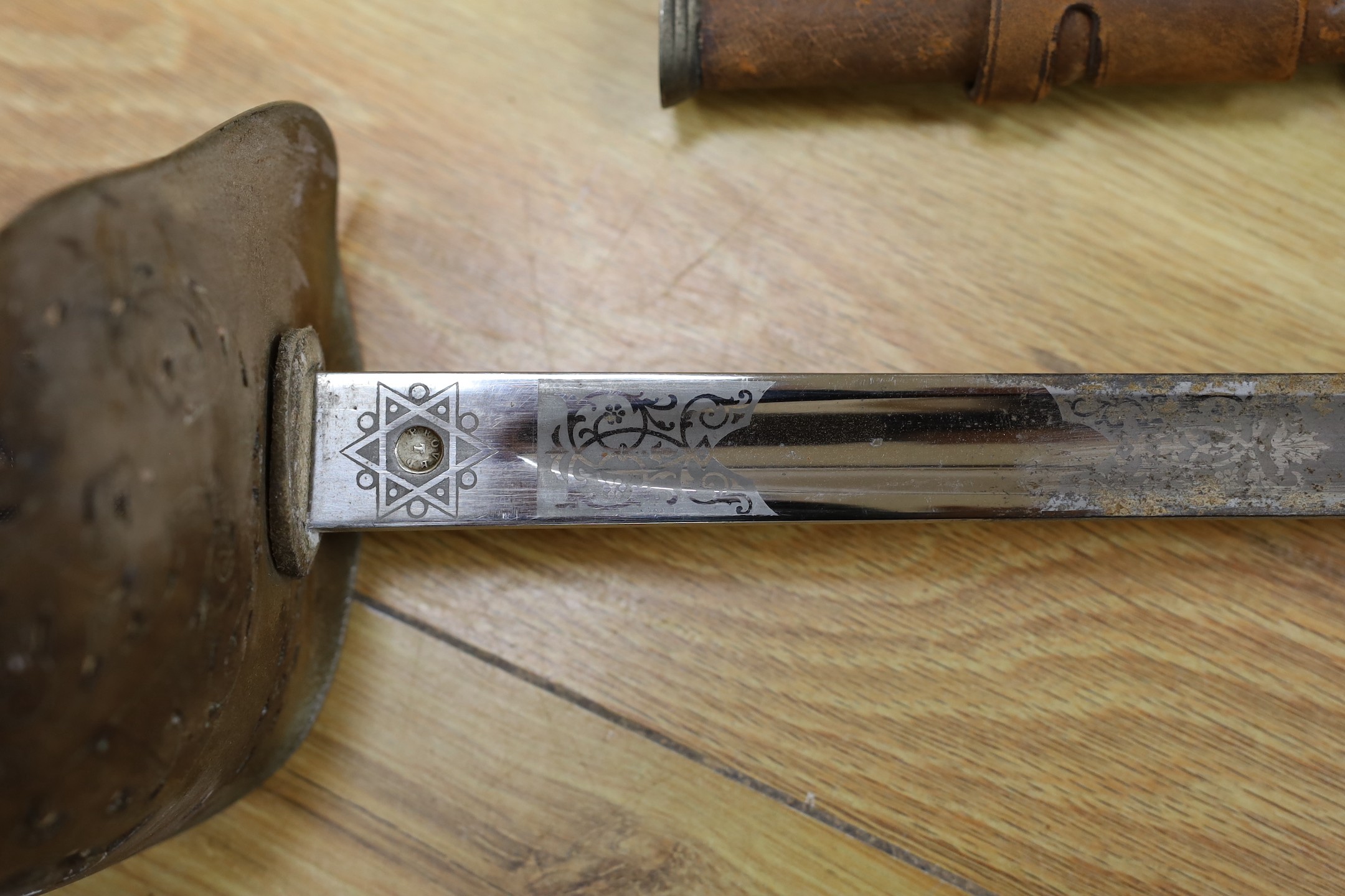 A George V military dress sword in brown leather covered scabbard, 102cm long, and a Middle Eastern dagger with carved and painted handle